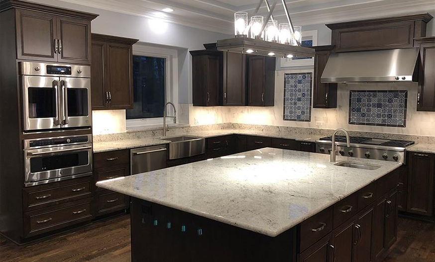 Spacious kitchen with dark wood cabinets, marble countertops, and stainless steel appliances. A chandelier adds elegance to the bright, modern space.